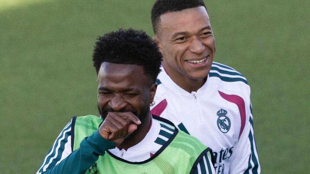 Vinicius Júnior, en primer plano con peto verde, y Kylian Mbappé sonríen durante un entrenamiento del Real Madrid contra el Leipzig en la Champions