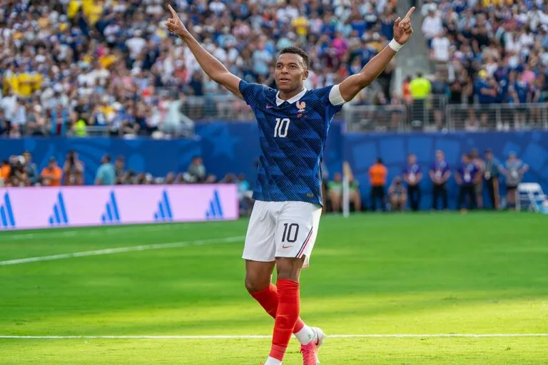 Kylian Mbappé celebra con los brazos en alto con la camiseta de Francia; el Real Madrid pide disculpas a China por sus palabras