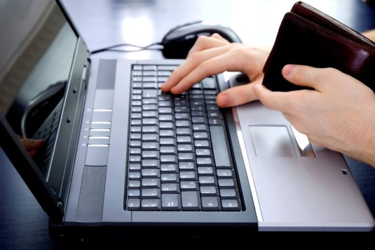 Remesas a Venezuela: una persona con su billetera en la mano hace un pago en línea desde una computadora portátil