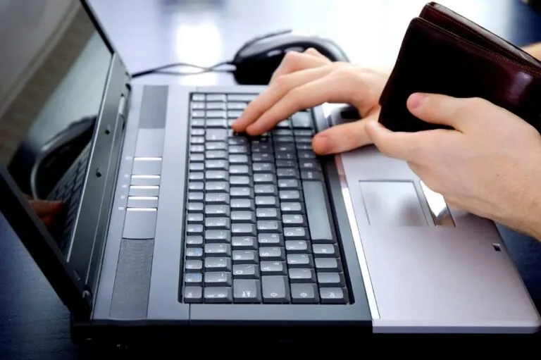 Remesas a Venezuela: una persona con su billetera en la mano hace un pago en línea desde una computadora portátil