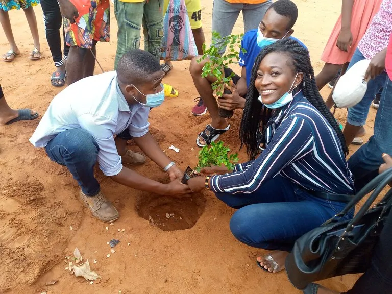 Jóvenes plantando un árbol durante una jornada de reforestación en Lomé, Togo