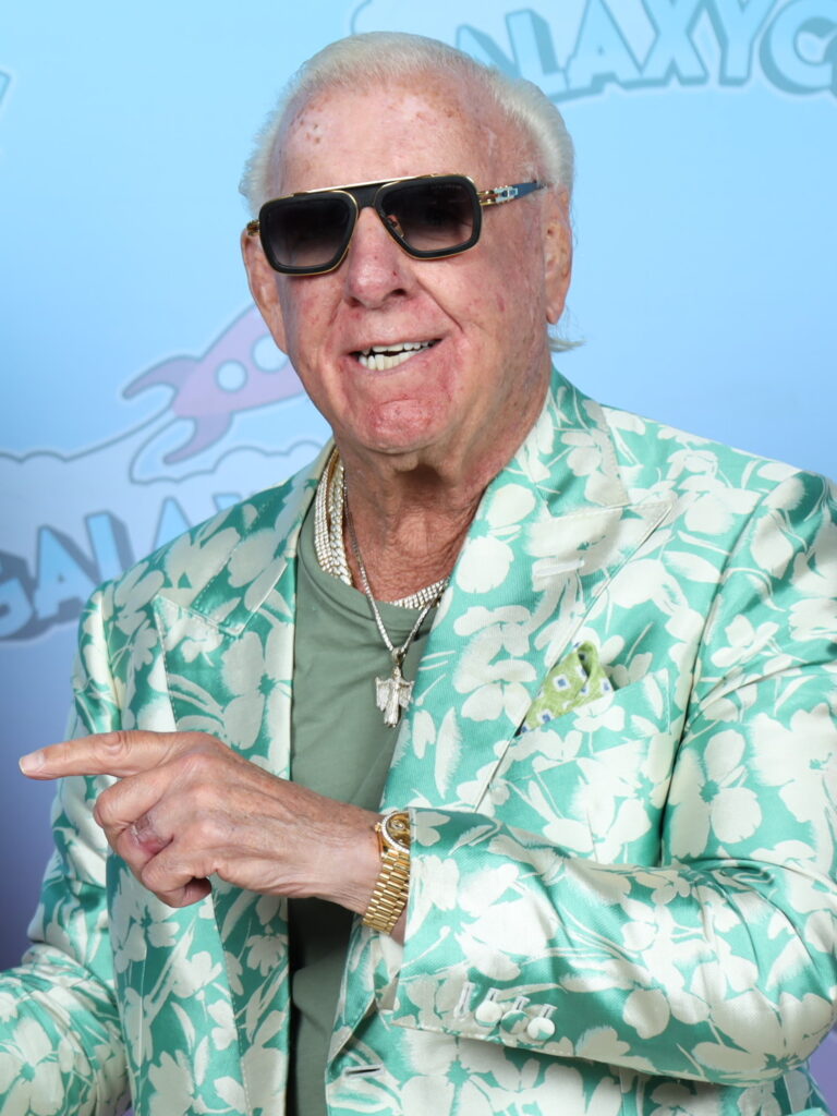 Ric Flair sonriendo con gafas de sol y una chaqueta floreada verde en el GalaxyCon Austin 2023