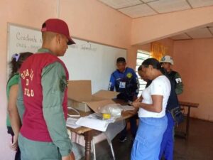 Una votante se registra en un centro electoral durante la Consulta Popular 2026 en Venezuela, junto a un efectivo de la Guardia del Pueblo