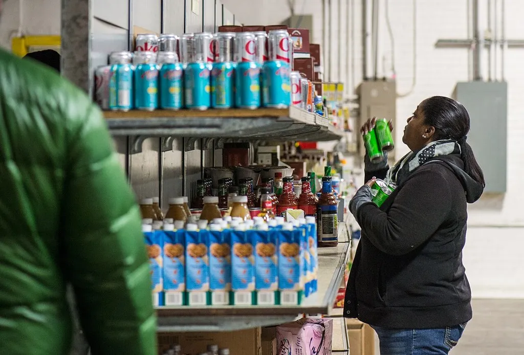 Una mujer escoge alimentos enlatados en un banco de alimentos mientras millones de familias se preparan para quedarse sin cupones de comida