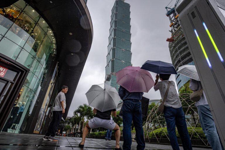 Tifón Champi en China: peatones con paraguas bajo la lluvia en Taipéi, con la torre Taipéi 101 al fondo