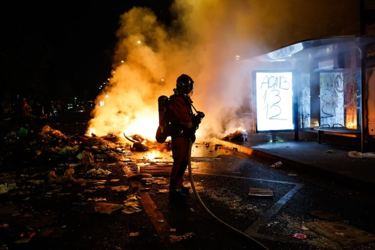 Un bombero junto a una barricada en llamas durante los disturbios en Francia, donde París aplicará un toque de queda en la plaza de la República y Les Halles