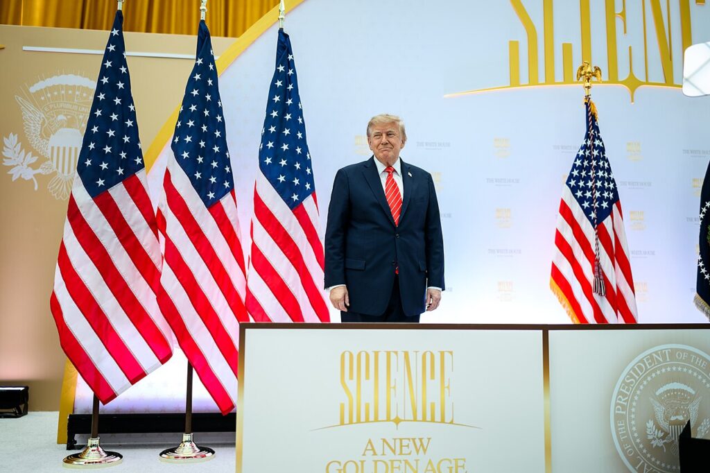 El presidente Donald Trump, de pie entre banderas de Estados Unidos en Washington, en una imagen de archivo relacionada con la nota en la que Trump acusa a Irán de encarecer el petróleo
